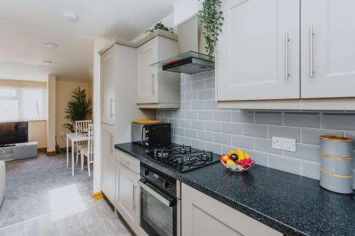 a kitchen with white cabinets and a black counter top at Cosy 2nd Floor Apartment - King Size Bed & Free Parking in Nottingham