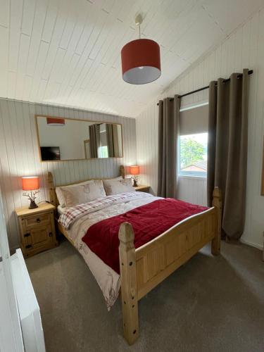 a bedroom with a wooden bed with a red blanket at Cherry tree Lodge in Dunoon