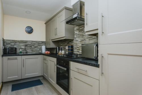 uma cozinha com armários brancos e bancadas pretas em Spacious 2nd Floor Apartment - King Size Bed & Free Parking em Nottingham