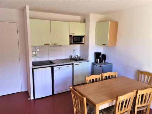une cuisine avec une table en bois et une table et des chaises dans l'établissement Appartement 2 Pièces pour 6 Personnes – Résidence Les Chalets d'Aurouze, La Joue du Loup - FR-1-504-464, à Saint-Étienne-en-Dévoluy