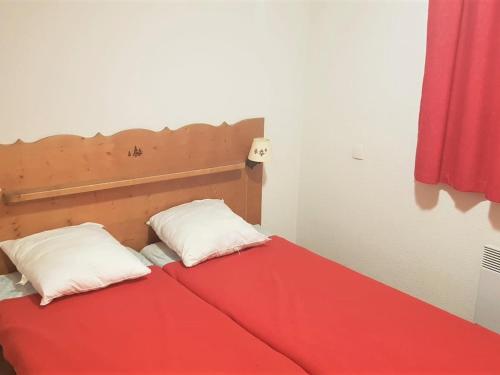 een rood bed met twee witte kussens erop bij Appartement La Joue du Loup, 2 pièces, 6 personnes - FR-1-504-482 in Le Dévoluy