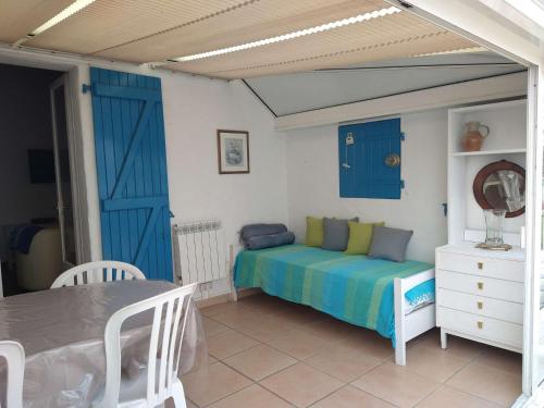 - une chambre avec un lit doté de portes bleues et d'une table dans l'établissement Maison 3 pièces avec véranda et jardin, à 300m de la plage - La Guérinière - FR-1-224B-98, à La Guérinière