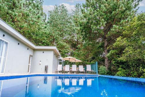 a swimming pool with chairs and an umbrella at Aconchegante apartamento em Campos do Jordão, região Capivari - PET friendly# in Campos do Jordão