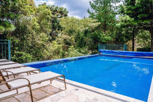 a swimming pool with chairs and trees in the background at Aconchegante apartamento em Campos do Jordão, região Capivari - PET friendly# in Campos do Jordão