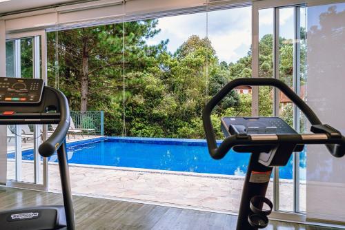 a gym with a treadmill and a swimming pool at Aconchegante apartamento em Campos do Jordão, região Capivari - PET friendly# in Campos do Jordão