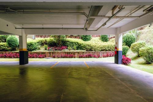 an empty parking garage with flowers in the background at Aconchegante apartamento em Campos do Jordão, região Capivari - PET friendly# in Campos do Jordão