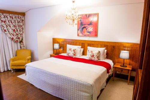 a bedroom with a large bed and a chandelier at Pousada das Lavandas in Campos do Jordão