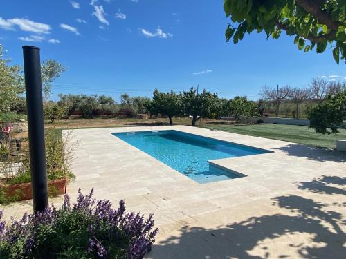 a swimming pool in a yard with purple flowers at Mas Les Oliveres in Vila-seca