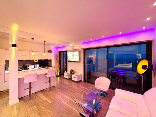 Il comprend un salon avec un canapé et une cuisine avec un éclairage violet. dans l'établissement SEA VIEW TOP FLOOR - PROMENADE DES ANGLAIS, à Nice