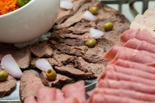 a plate of food with meat and green olives at Le Ndiambour Hôtel et Résidence in Dakar