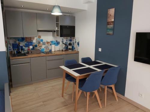 a kitchen with a table and blue chairs at Apartament Niebieski z tarasem in Szczyrk
