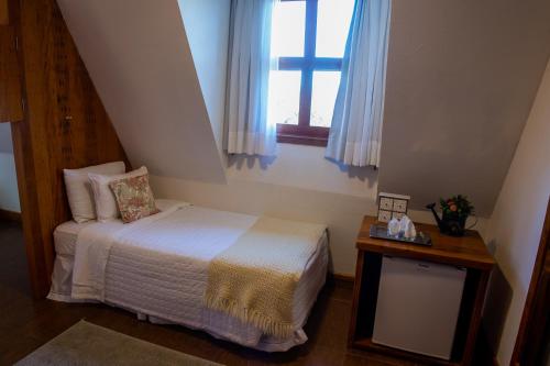 a small bedroom with a bed and a window at Pousada das Lavandas in Campos do Jordão