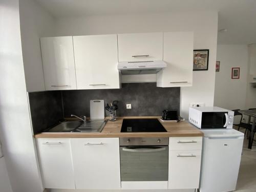 une cuisine avec des armoires blanches et un évier dans l'établissement Appartement Rénové avec Cuisine Américaine et WIFI, Proche des Thermes Saint Roch - FR-1-541-32, à La Roche-Posay