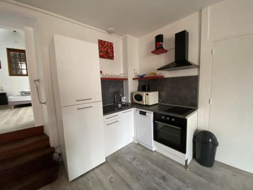 une petite cuisine avec des armoires blanches et un micro-ondes dans l'établissement Appartement 57m² avec WIFI à 200m des Thermes – 4 pers. – Parking gratuit – La Roche-Posay - FR-1-541-40, à La Roche-Posay