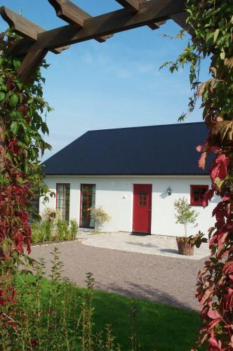 a white building with a black roof and red doors at Hotel Bella Luna in Båstad