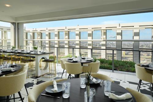 a restaurant with tables and chairs and a large window at Hyatt House LAX Century Blvd in Los Angeles