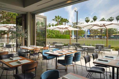 a restaurant with tables and chairs and umbrellas at Hyatt House LAX Century Blvd in Los Angeles