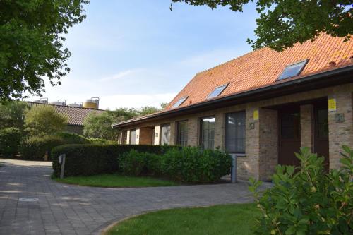 une maison en briques avec un toit en carrelage et une allée. dans l'établissement DE MEIBOOM vakantiehoeve tot 21 pers, à Langemark