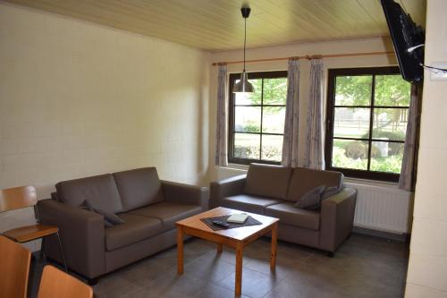 een woonkamer met 2 banken en een salontafel bij DE MEIBOOM vakantiehoeve tot 21 pers in Langemark