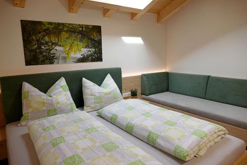 a bedroom with two beds and a couch with pillows at Der Luemerhof in Marlengo