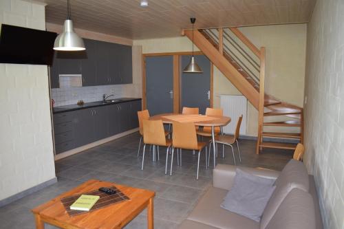 Il comprend une cuisine et un salon avec une table et des chaises. dans l'établissement DE MEIBOOM vakantiehoeve tot 21 pers, à Langemark
