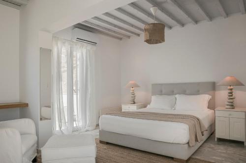 a white bedroom with a white bed and a chair at Villa Argo by Mykonos Top Villas in Houlakia