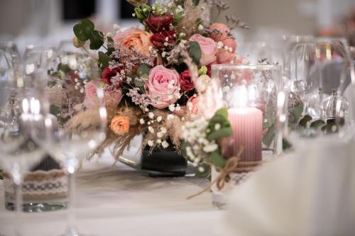 a table with a centerpiece of flowers and a candle at Schloss Rattey in Schönbeck