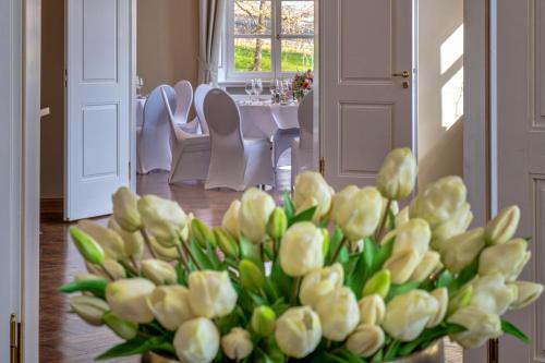 a vase filled with white flowers in a room at Schloss Rattey in Schönbeck