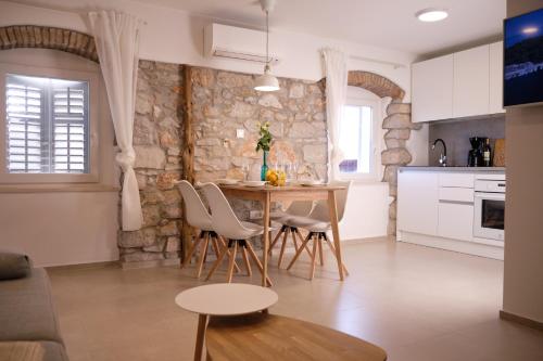 a kitchen with a table and chairs and a stone wall at Apartment House Bucul in Mali Lošinj