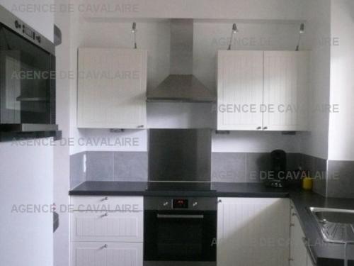 - une cuisine avec des placards blancs et une cuisinière noire dans l'établissement Appartement T3 Centre-Ville: Balcon, Ascenseur, 2 Chambres, Équipé, Capacité 6 Personnes - FR-1-100-217, à Cavalaire-sur-Mer