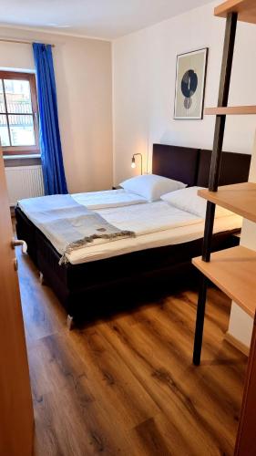 a bedroom with a large bed with a wooden floor at Family Apartment Bacchus in Marlengo