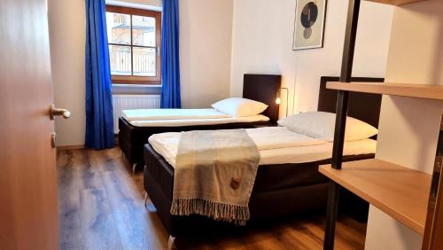 2 camas en una habitación pequeña con cortinas azules en Boutique Appartamento Bacchus, en Marlengo