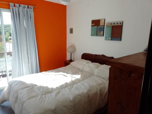 Un dormitorio con una pared de color naranja y una cama en Cerro Encanto, en Potrero de los Funes
