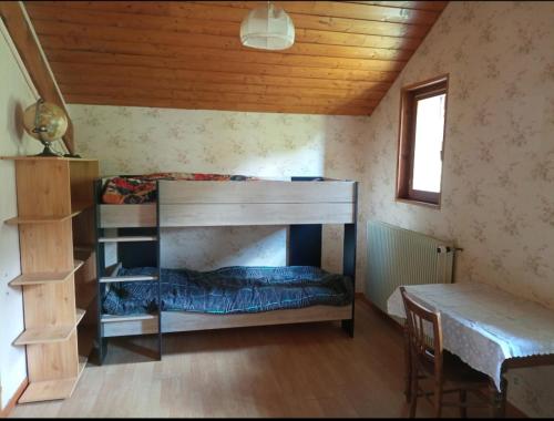 Chez Mémé Cour في بيلوفو: غرفة صغيرة مع سرير بطابقين وطاولة