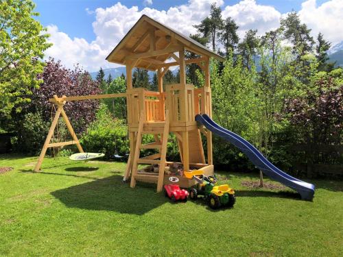 a wooden playset with a slide and toys on the grass at Appartement Mama in Haus im Ennstal