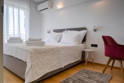 a bedroom with a bed with white sheets and a red chair at Villa Diosa de la Aurora in Klis