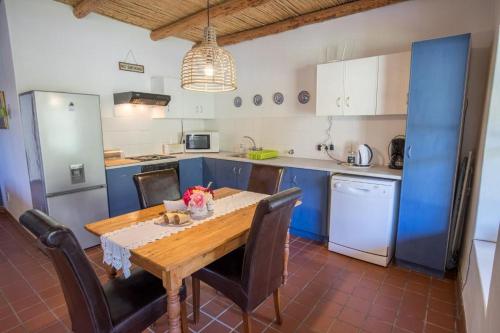 een keuken met een houten tafel en blauwe kasten bij Harmonie Farm Cottages in Montagu