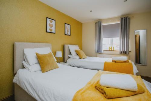 duas camas num quarto de hotel com paredes amarelas em 2 Bedroom Garden Apartment Near QMC, Tennis Centre & City em Nottingham