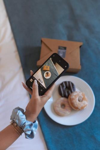 a person taking a picture of a plate of doughnuts at 7Rizes Luxury Living in Heraklio Town