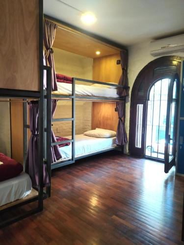 a room with three bunk beds and a wooden floor at MedioMundo Hostel in Montevideo