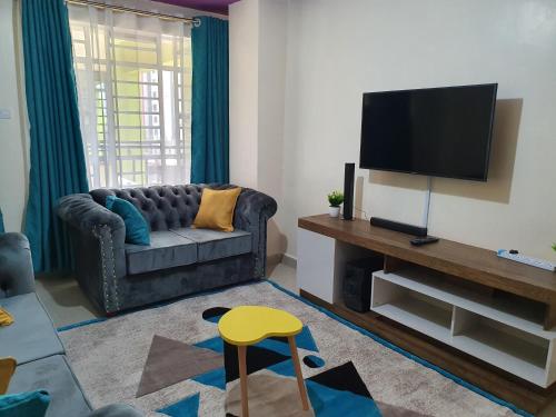 a living room with a couch and a flat screen tv at Luxurious and Comfy One bedroom in Ruiru, along thika road in Ruiru