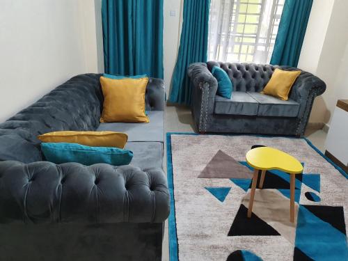 a living room with a couch and a yellow stool at Luxurious and Comfy One bedroom in Ruiru, along thika road in Ruiru