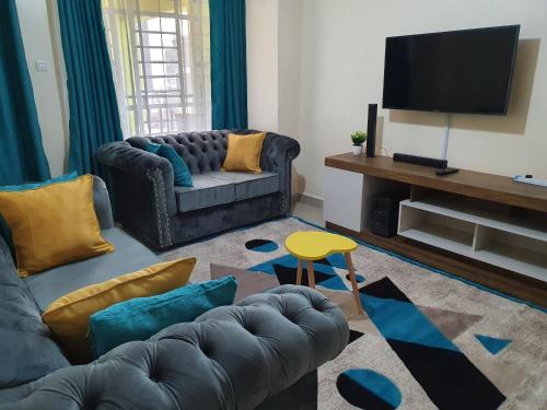 a living room with a couch and a television at Luxurious and Comfy One bedroom in Ruiru, along thika road in Ruiru