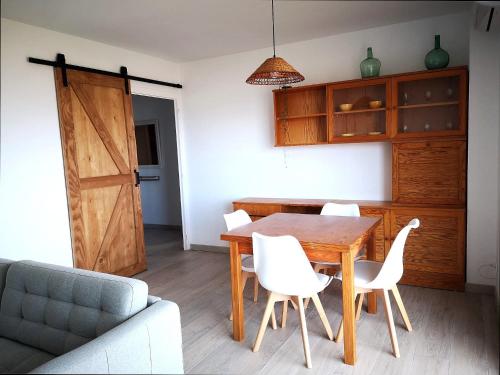une salle à manger avec une table en bois et des chaises blanches dans l'établissement ÁTICO FRENTE AL MAR, à Canet de Mar