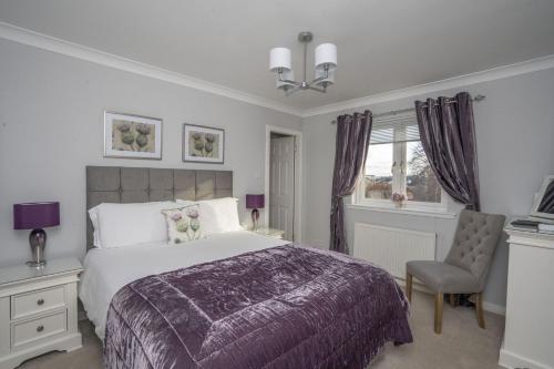 a bedroom with a large bed and a chair at Springfield Lodge Bed and Breakfast in Stirling