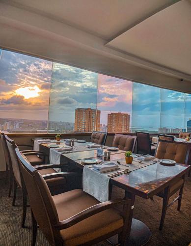a restaurant with a long table with chairs and a large window at Hotel Dann Carlton Barranquilla y Centro de Convenciones in Barranquilla