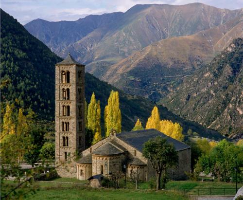 an old building in a field with mountains in the background at Racó del Pirineu in El Pont de Suert