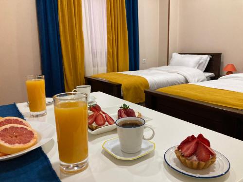 a table with a breakfast of fruit and orange juice at Borjomi Yellow Hotel in Borjomi