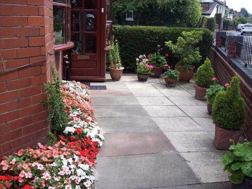 um passeio com flores em vasos ao lado de um edifício em Butterfly Guest House em Cheadle