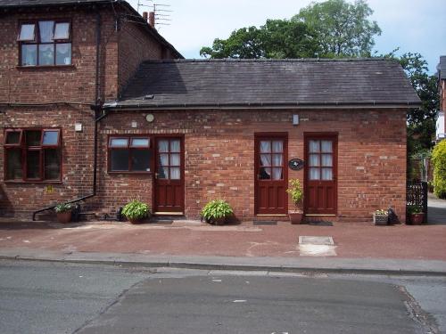 a brick building with red doors on a street at Butterfly Guest House in Cheadle